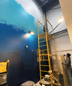 Matt Lively helps artist Shaylen Amanda Broughten at work on her mural